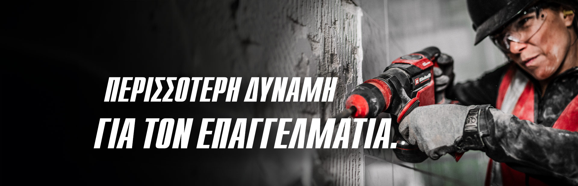 Ένα άτομο που φοράει προστατευτικά γυαλιά και κράνος χρησιμοποιεί ένα κόκκινο τρυπάνι σε τοίχο, με το κείμενο «Περισσότερη δύναμη για την επαγγελματία».