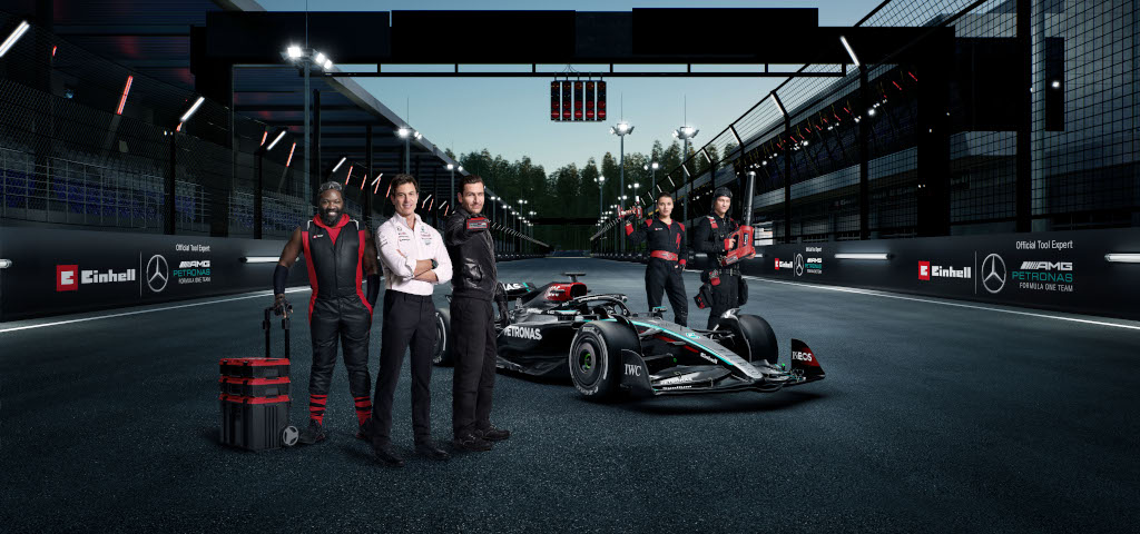 five e team members stand around formula 1 car