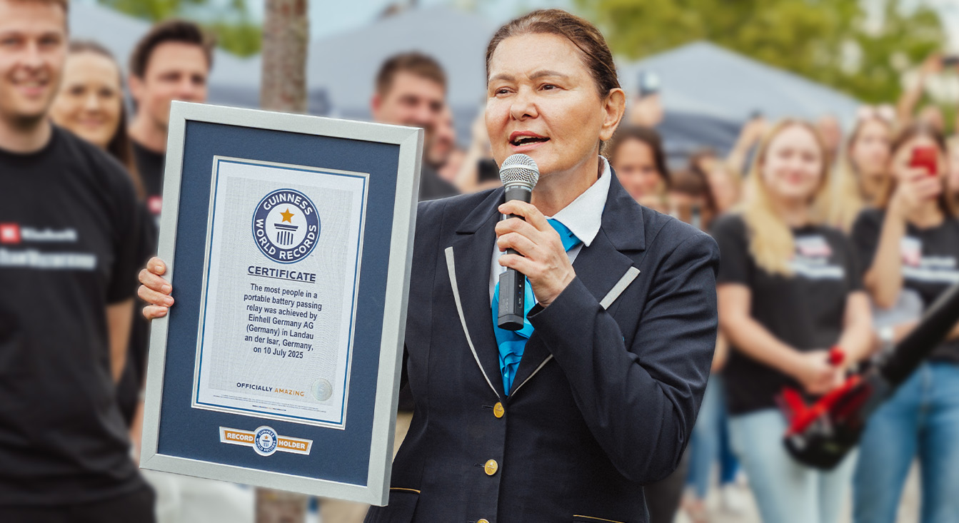 A woman in official Guinness attire holds a certificate for Einhell’s battery passing relay world record.